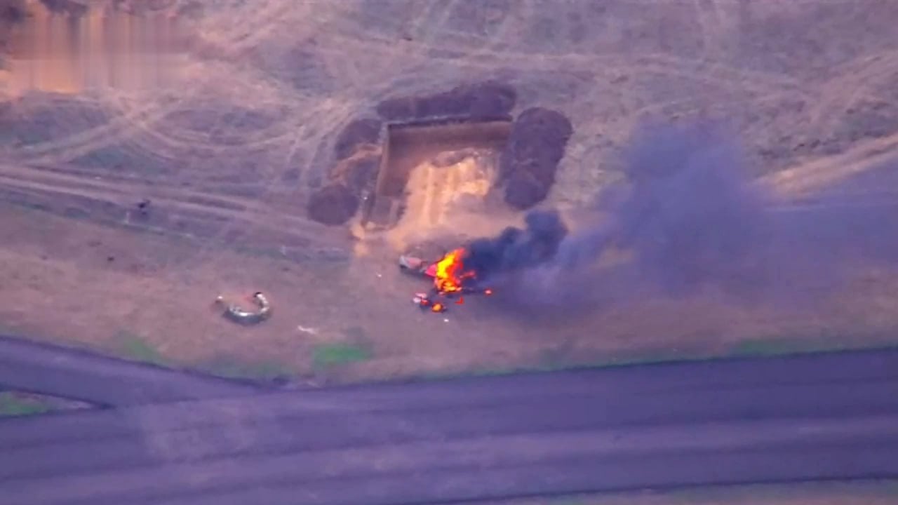 An aerial image shows a small aircraft engulfed in flames.